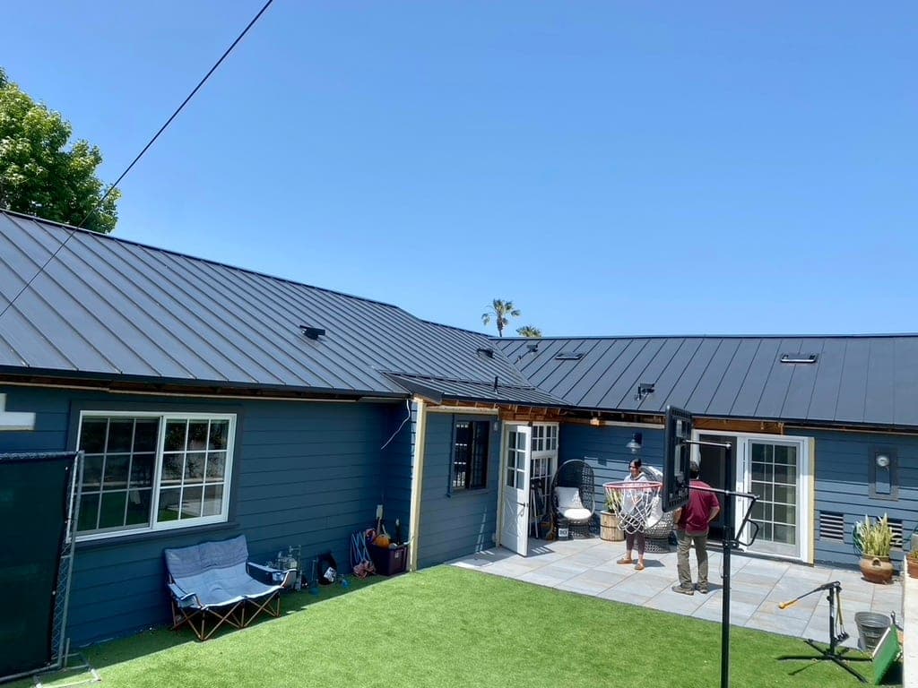 Coastal Carlsbad home with a charcoal standing-seam metal roof overlooking the Pacific Ocean at golden hour